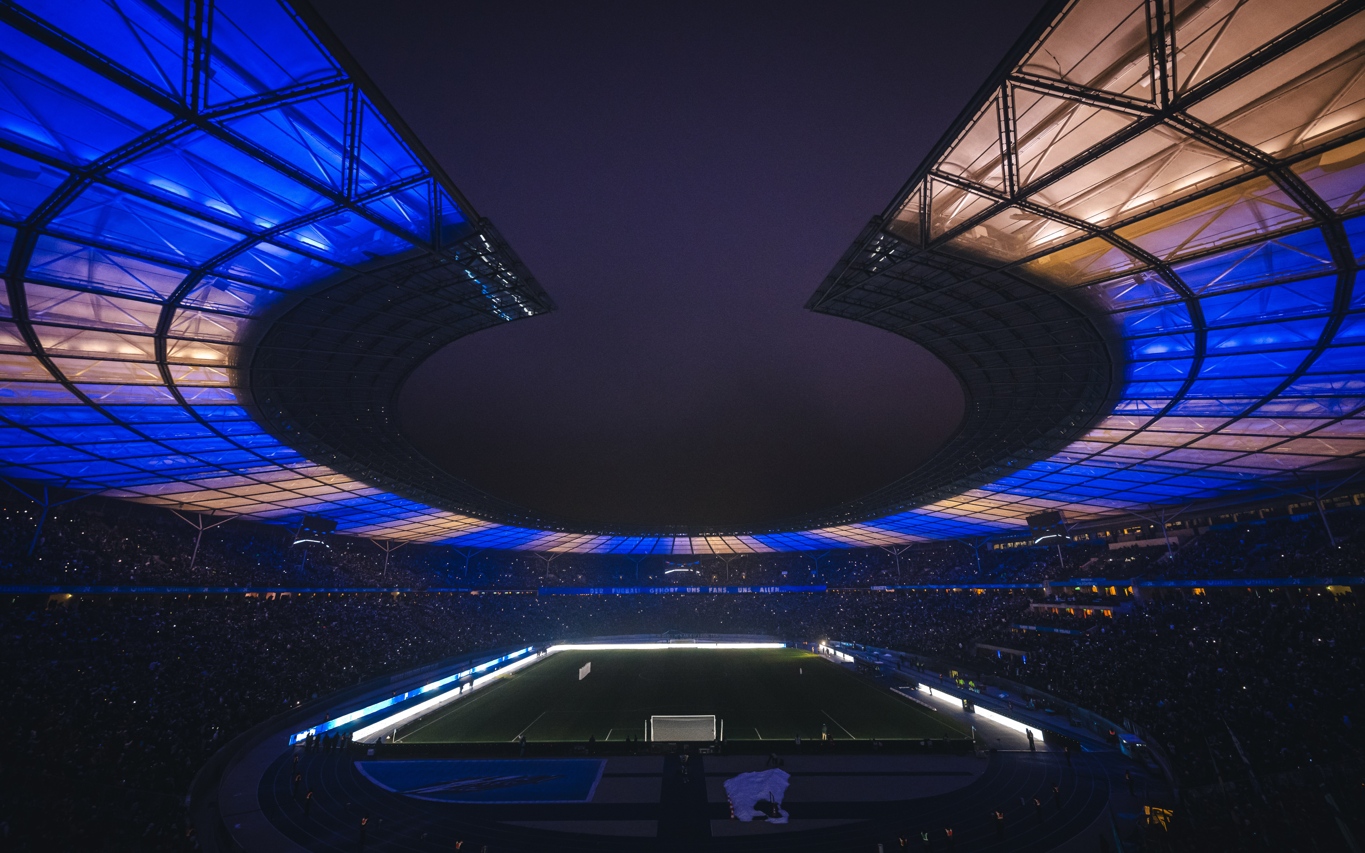 Blau-weißes Licht erleuchtet das dunkle Olympiastadion.