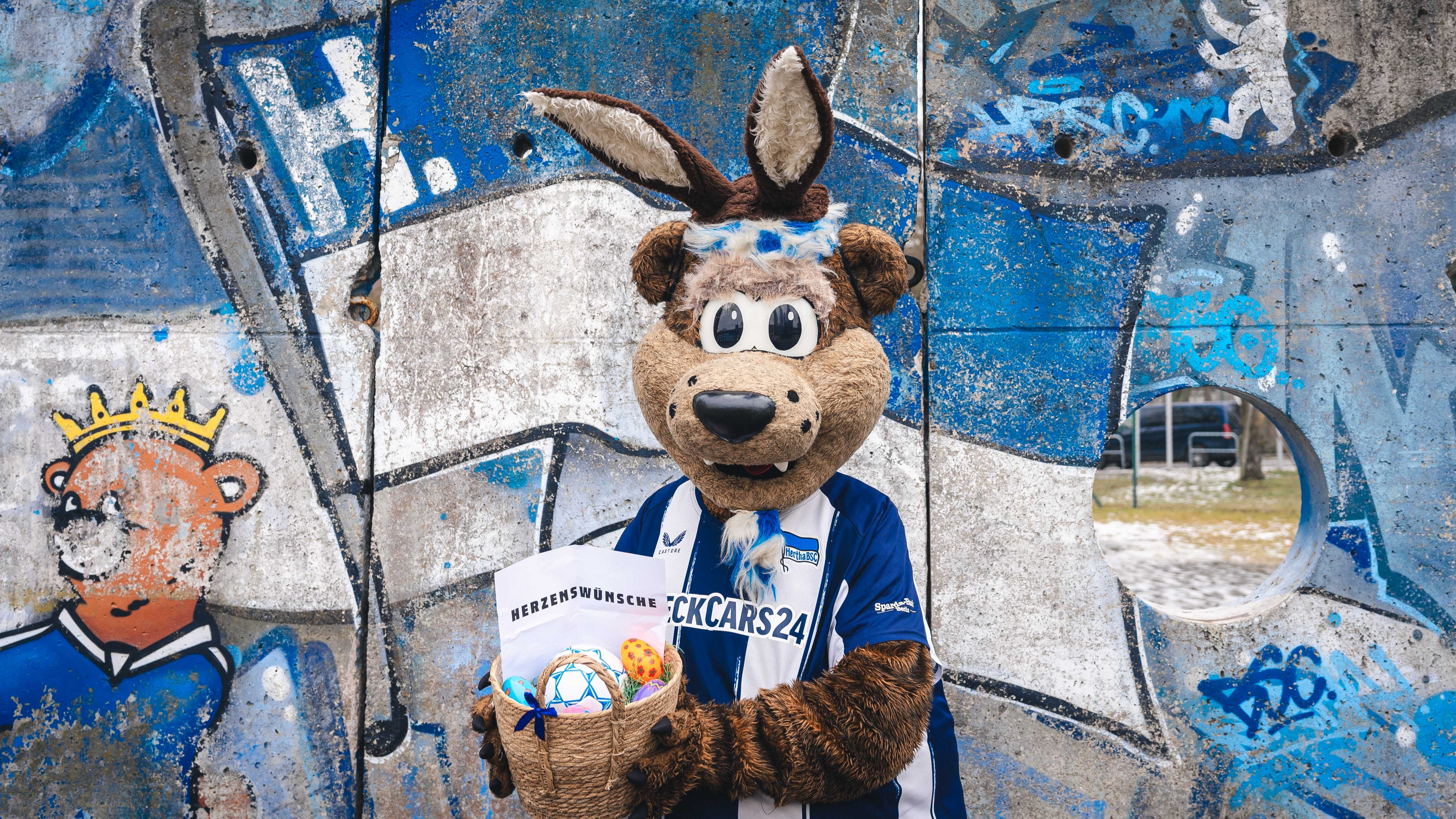 Herthinho vor der Mauer mit Osterkorb.