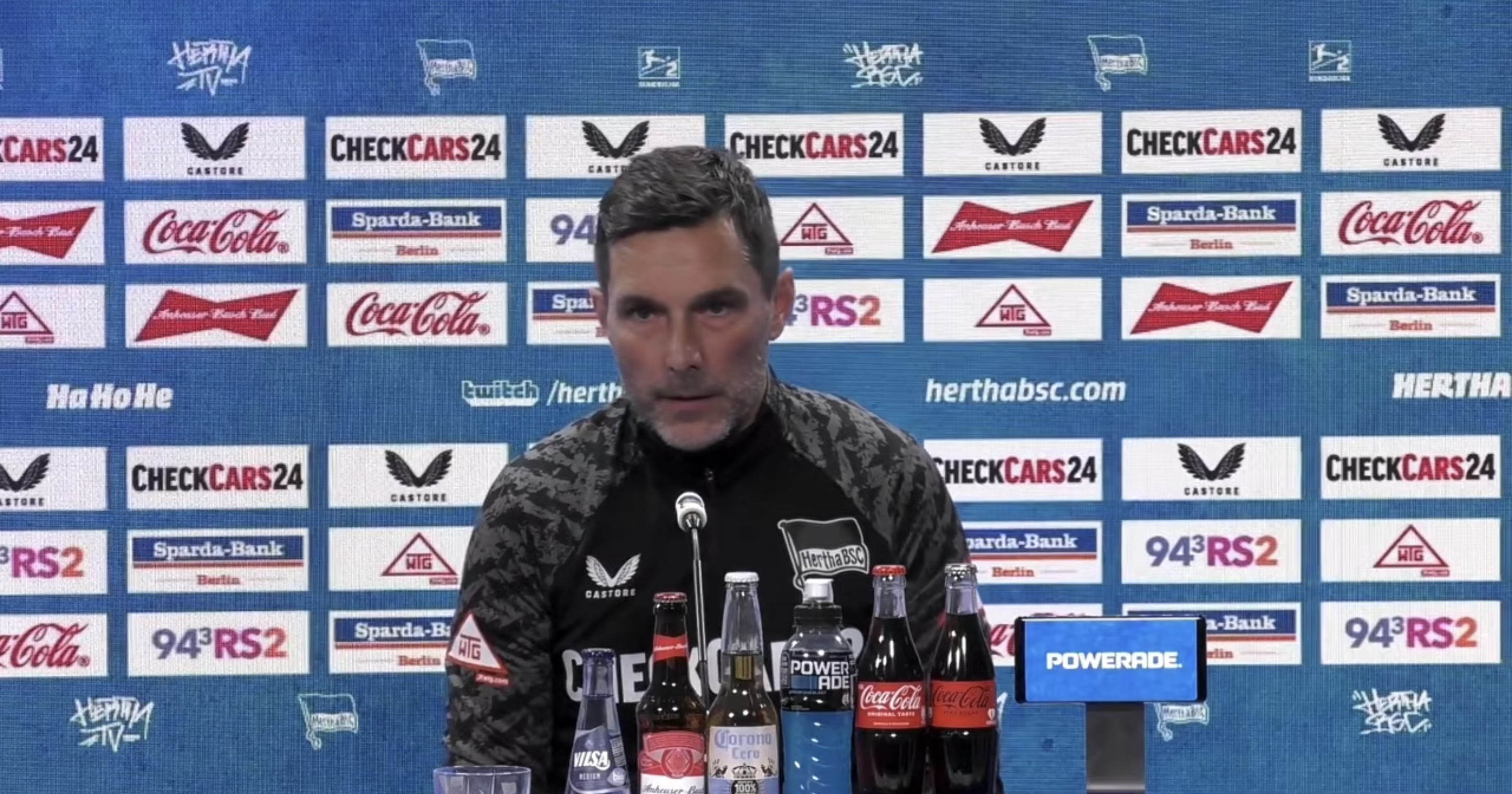 Stefan Leitl sitzt bei der Pressekonferenz auf dem Podium.