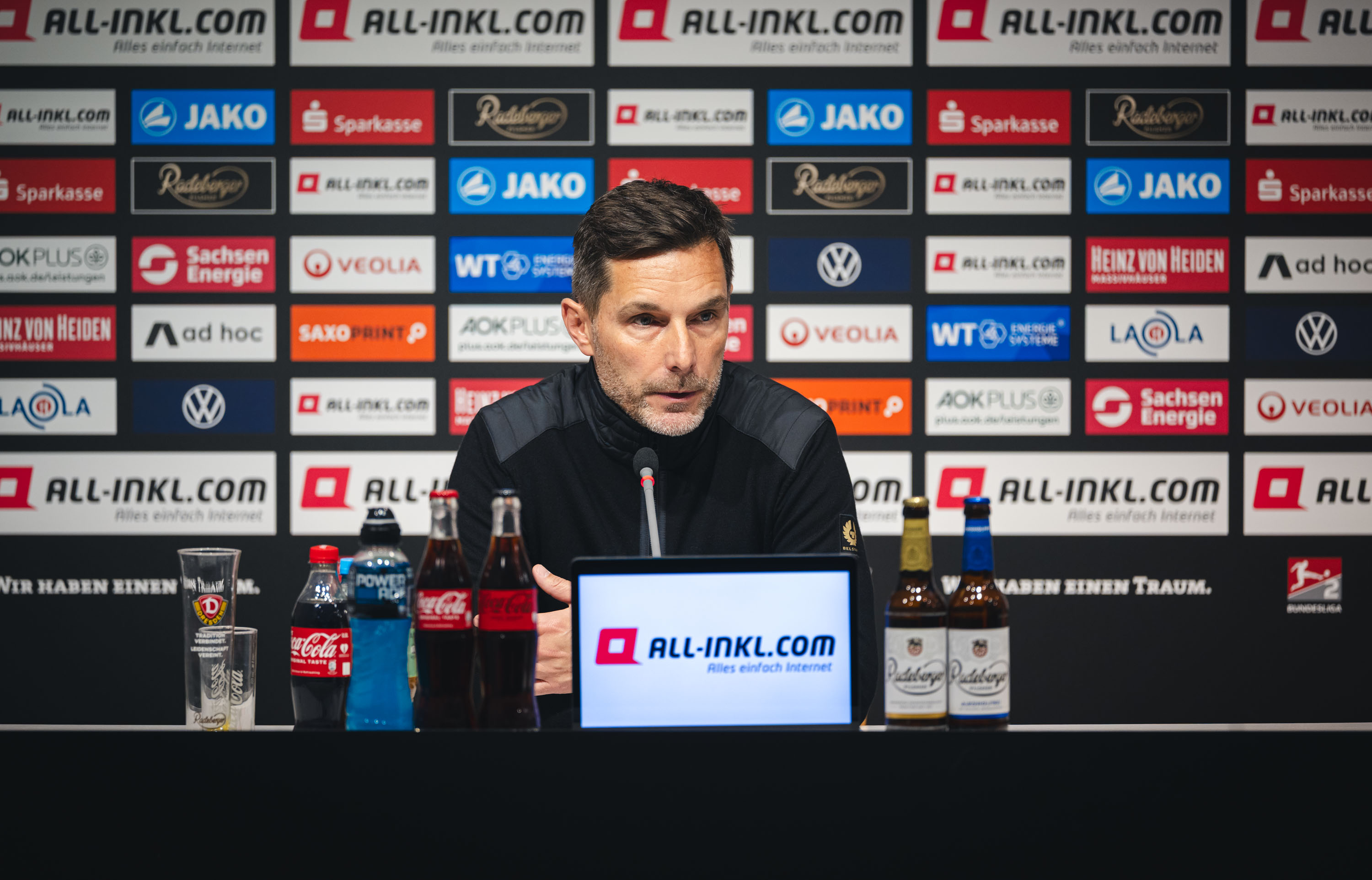 Stefan Leitl sitzt bei der Pressekonferenz auf dem Podium.
