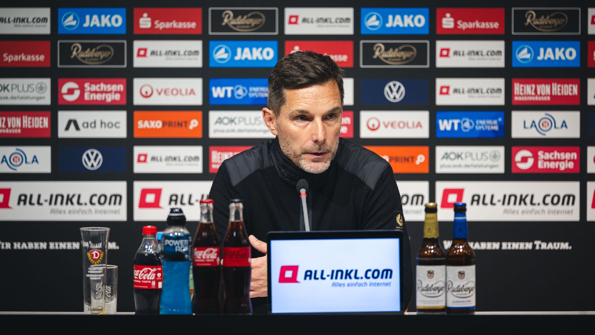 Stefan Leitl sitzt bei der Pressekonferenz auf dem Podium.