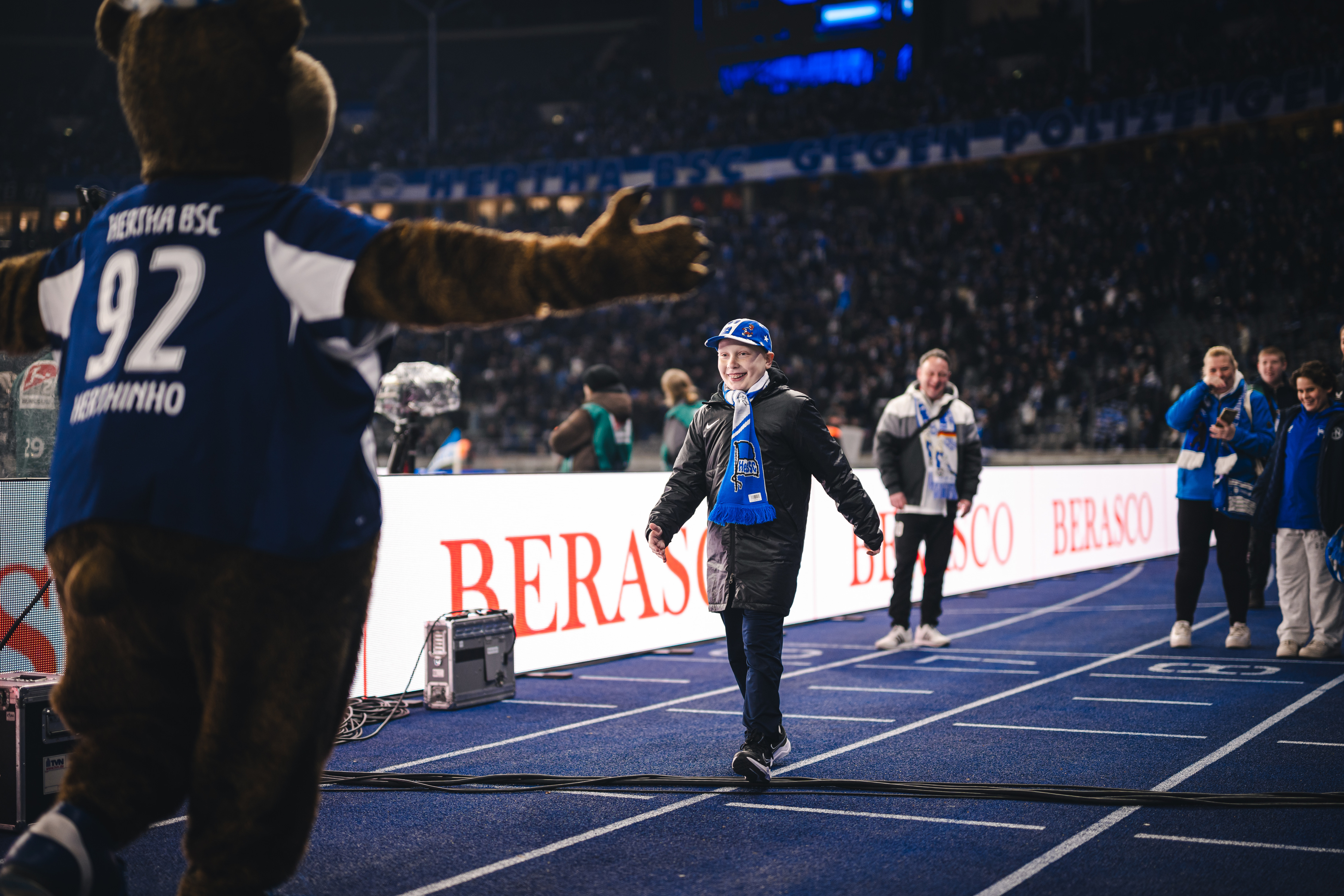 Ein junger Herthaner läuft auf Herthinho zu.