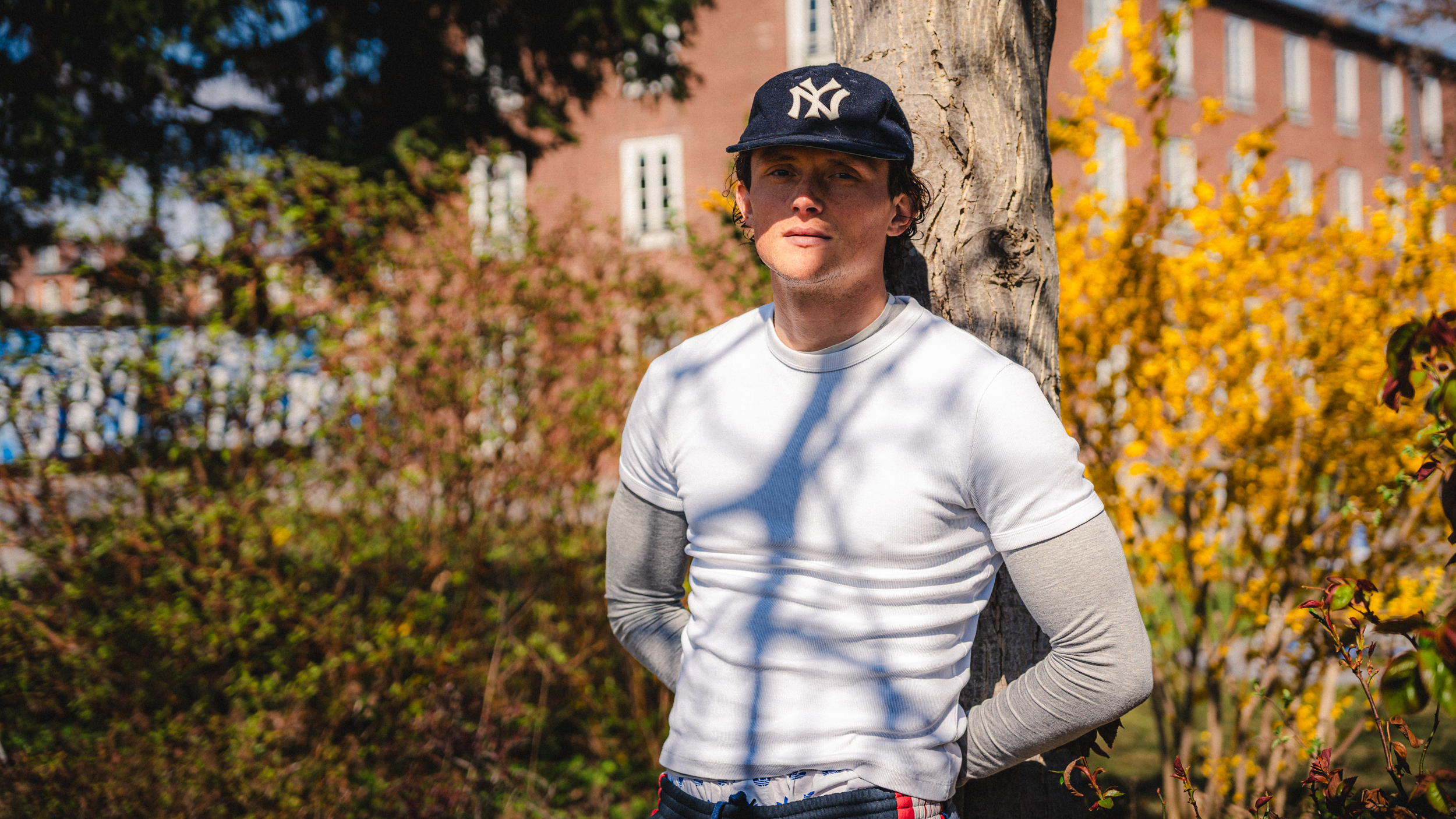 Fabian Reese lehnt an einen Baum vor der Geschäftsstelle.