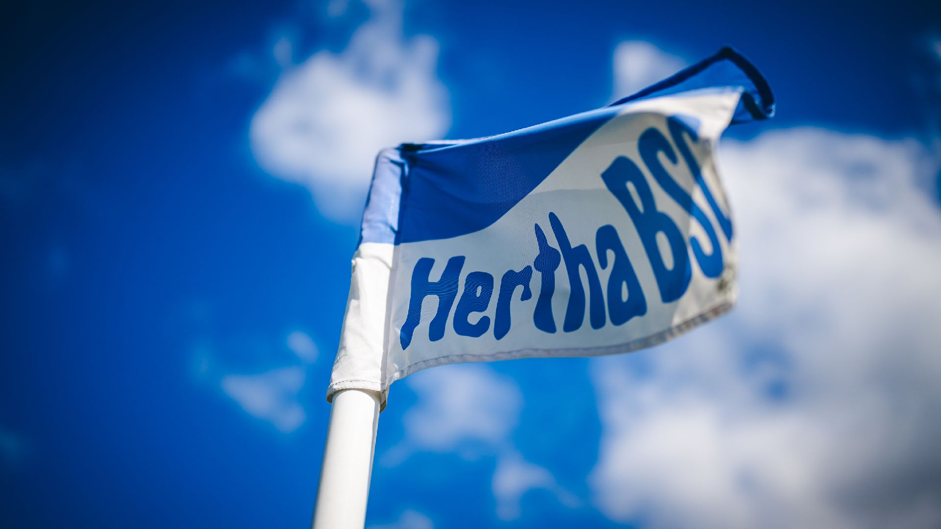 A hertha flag in front of clouds.