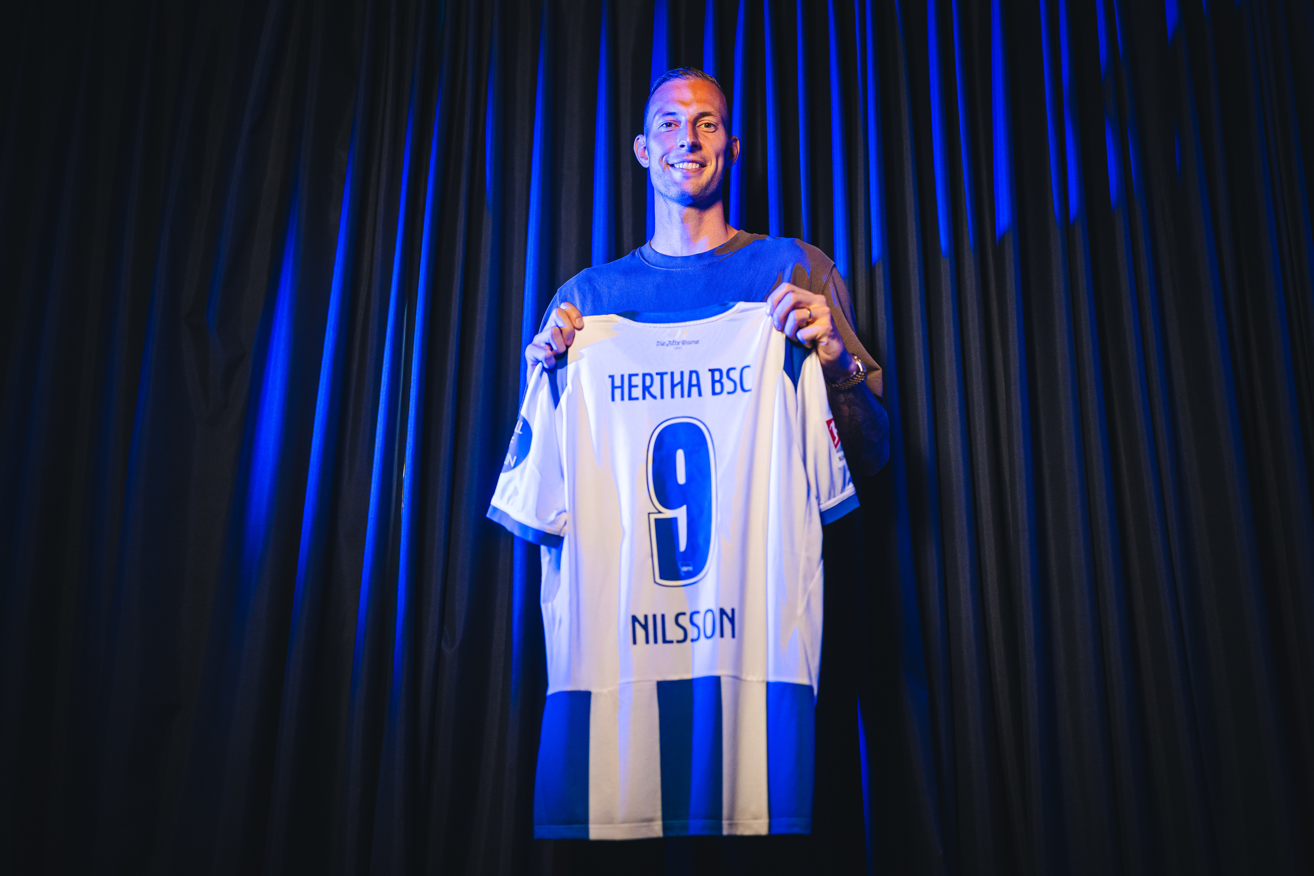 Gustaf Nilsson hält ein Trikot mit seiner Rückennummer in die Kamera.