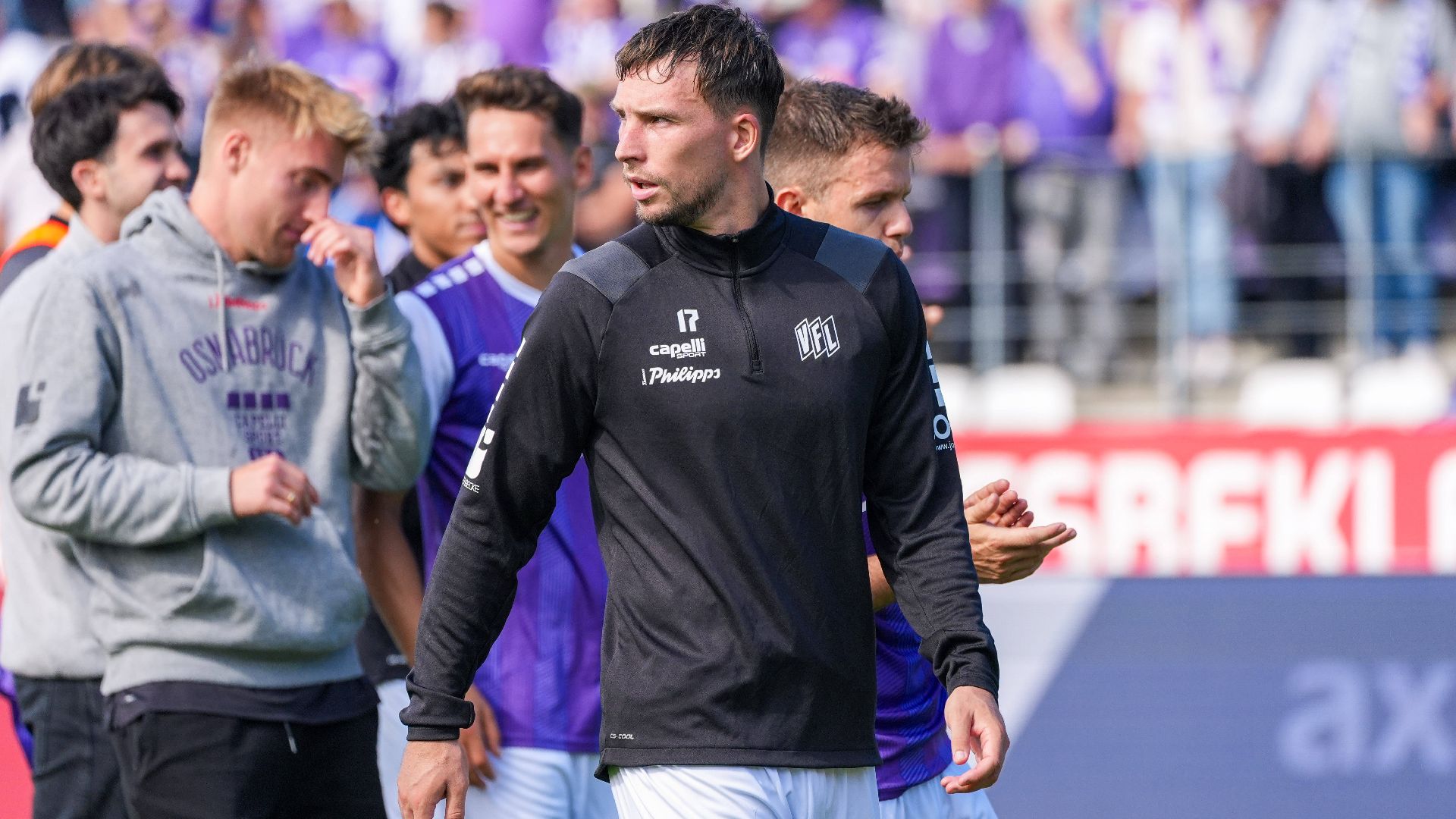 Robin Meißner geht mit seinen Osnabrücker Teamkollegen über den Rasen.