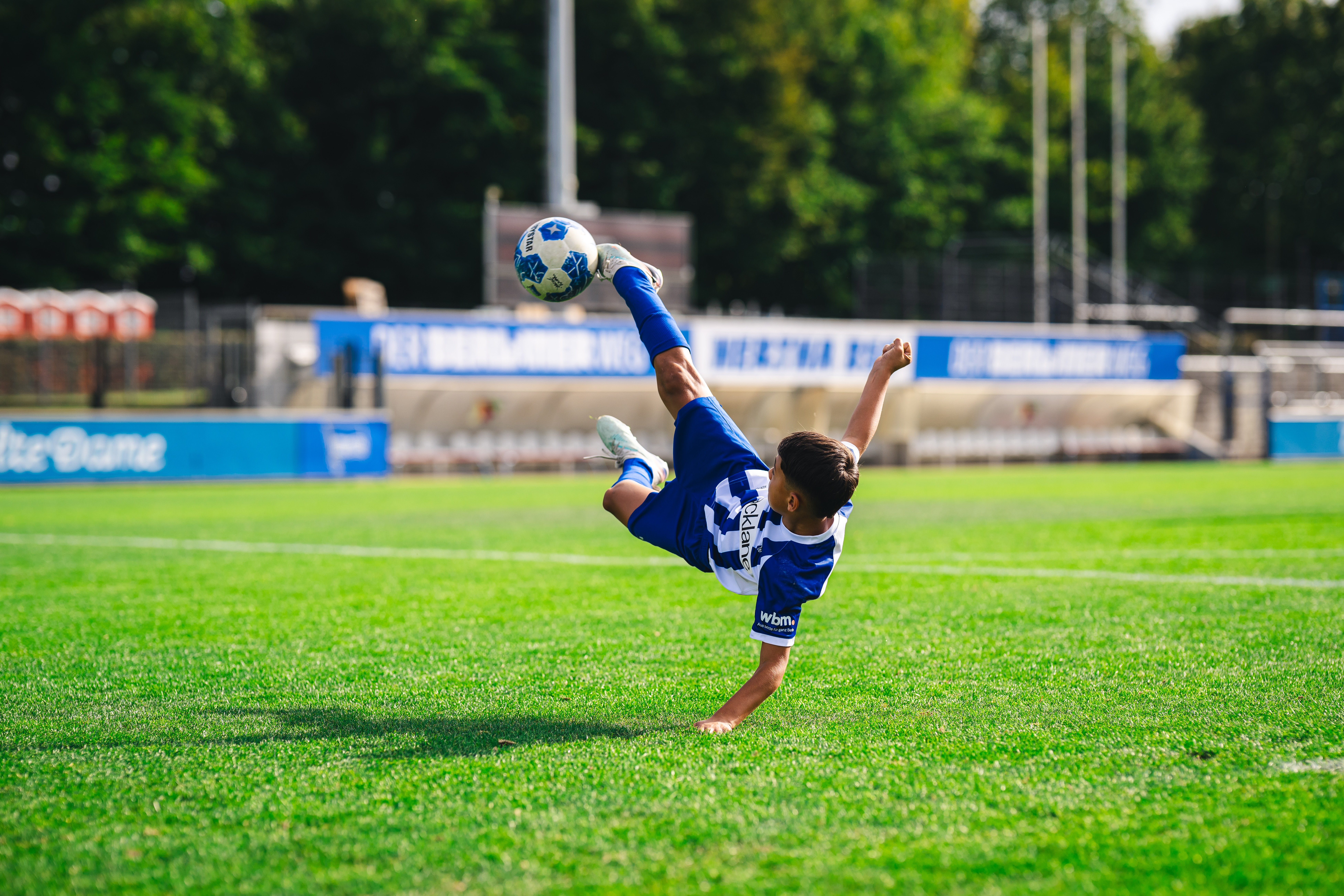 Ein Junge im Trikot der Fußballschule macht einen Fallrückzieher.