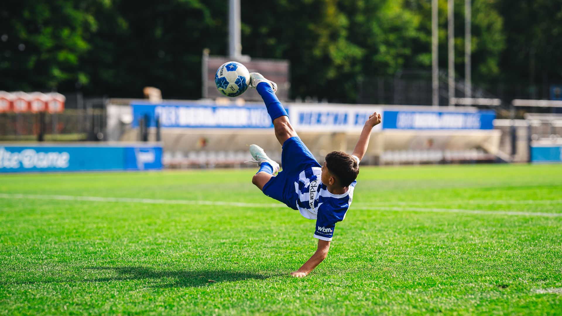 Ein Junge im Trikot der Fußballschule macht einen Fallrückzieher.