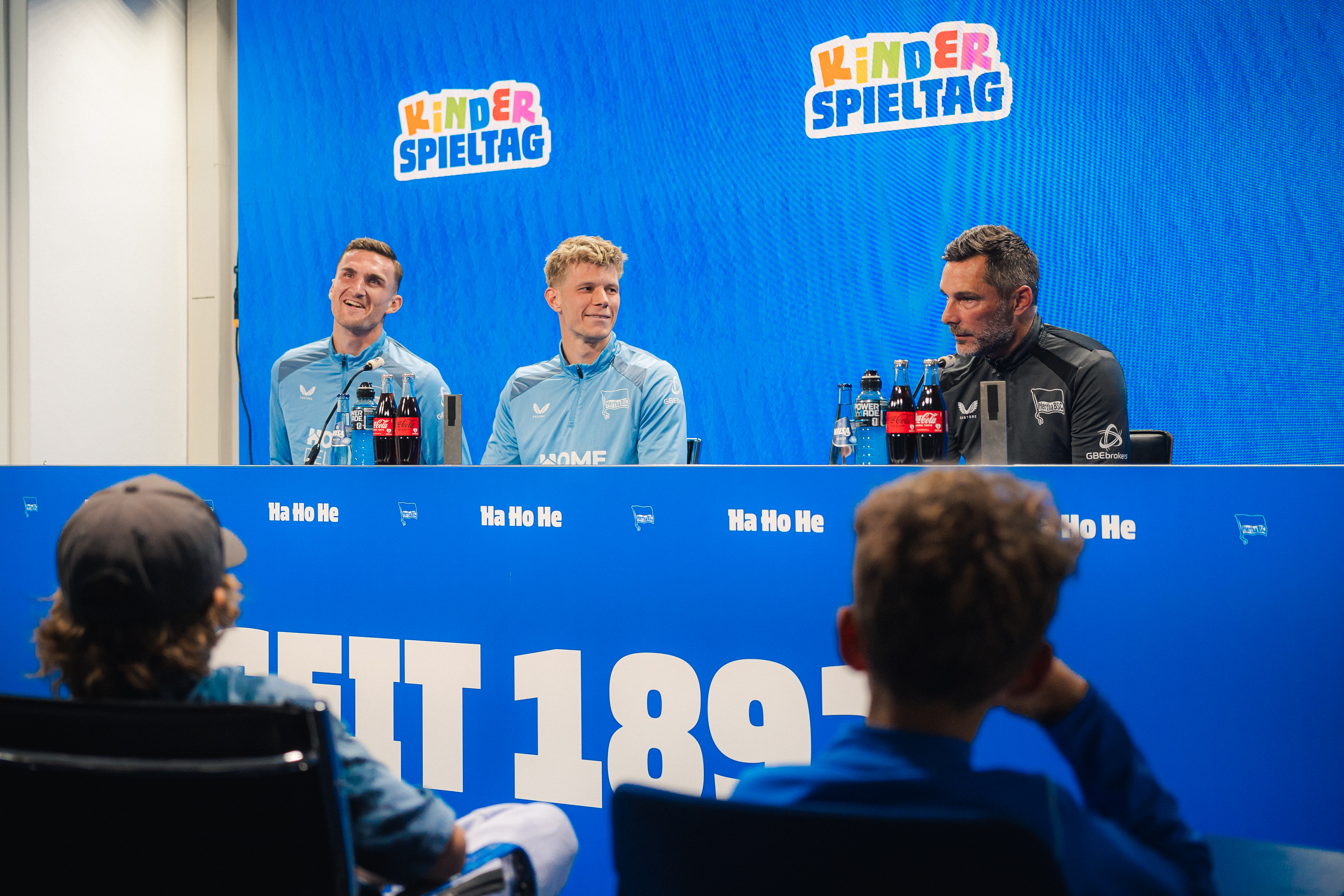 Niklas Kolbe, Luca Schuler und Stefan Leitl auf der Kinder-PK, dazu zwei Kinder die sich für Fragen melden.