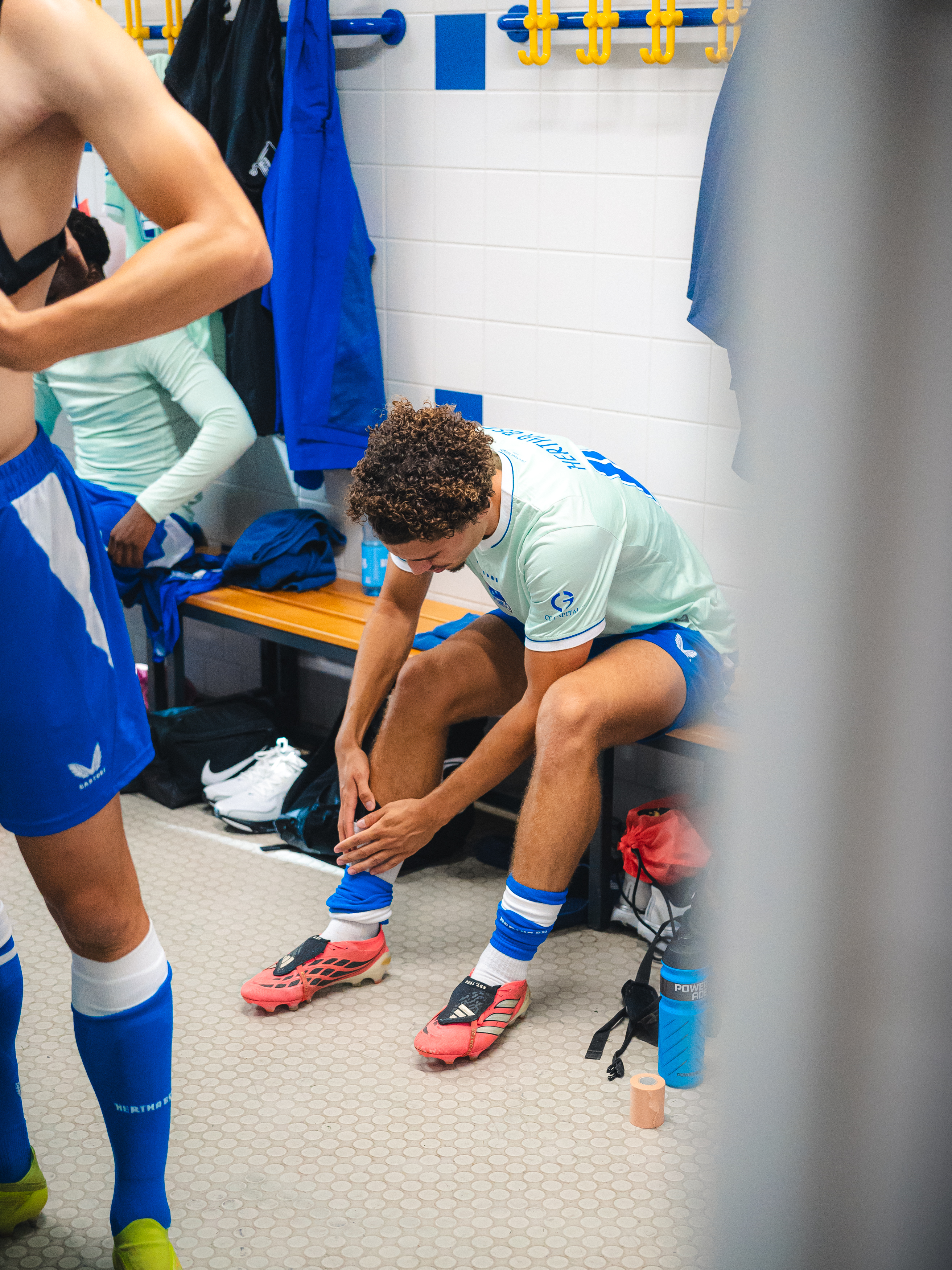 Ein Spieler richtet sich in der Kabine die Stutzen zurecht.