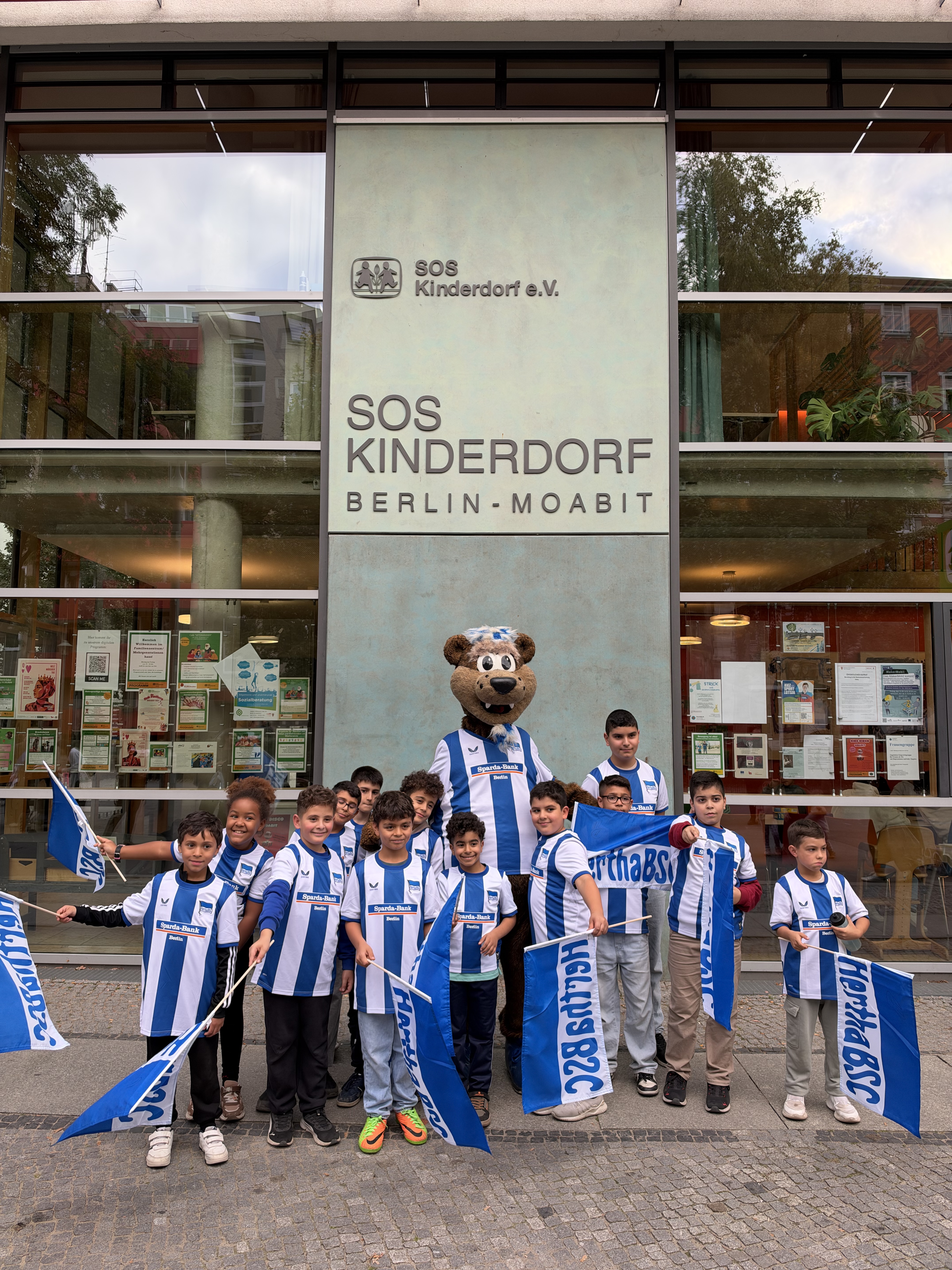 Herthinho mit Kindern vom SOS Kinderdorf Berlin in blau-weißen Trikots.