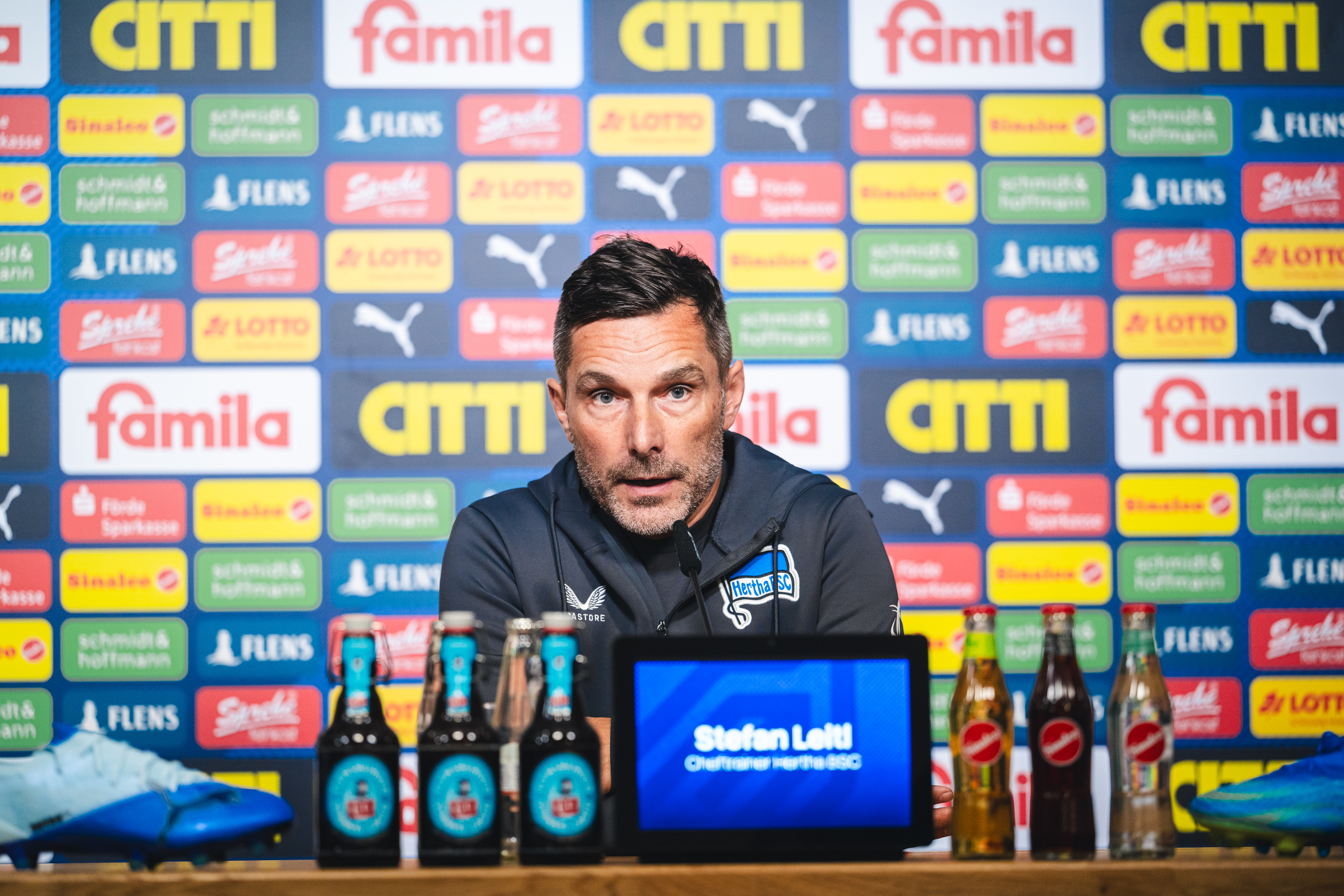 Stefan Leitl sitzt bei der Pressekonferenz auf dem Podium.