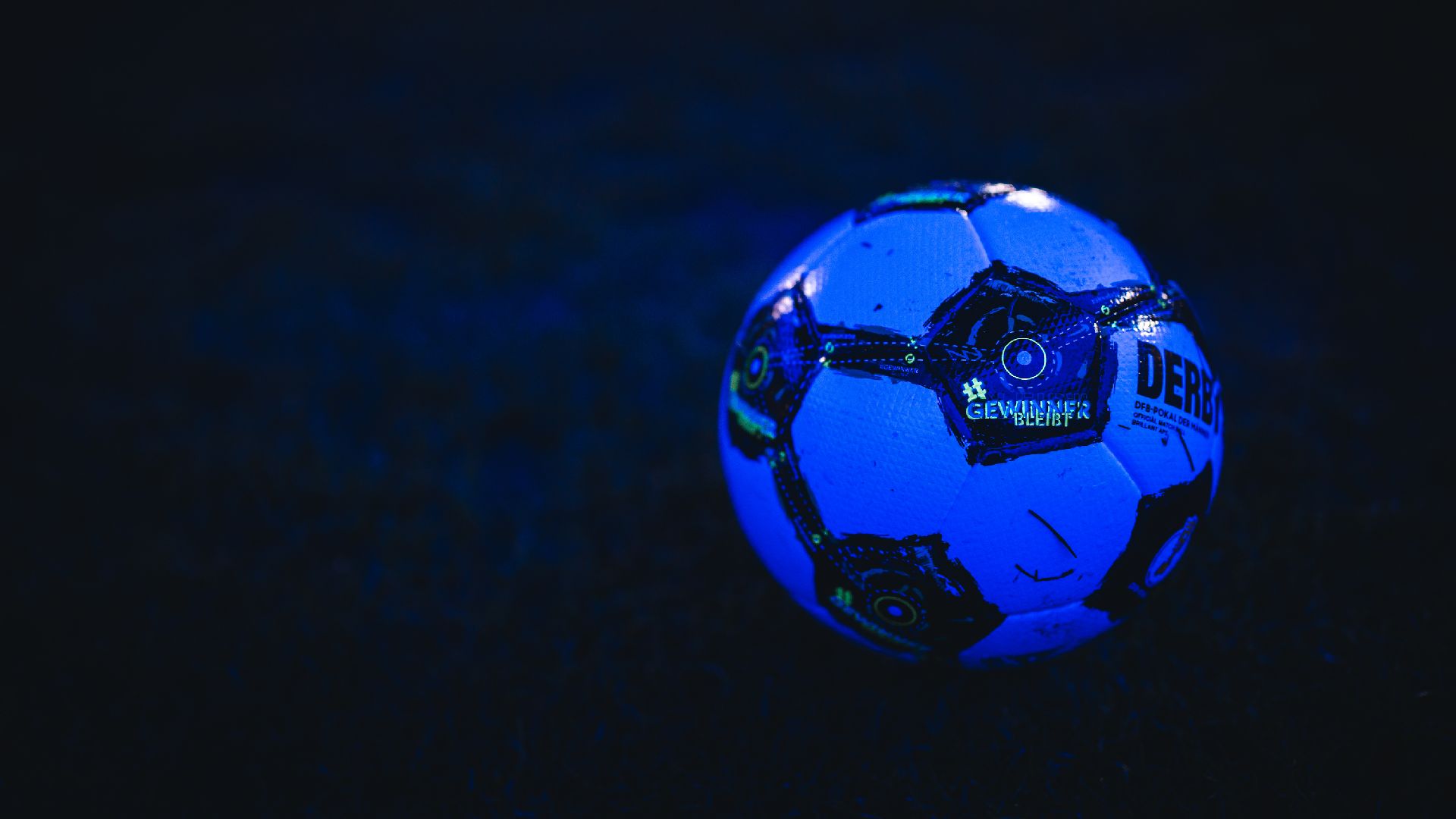 Der Spielball des DFB-Pokals liegt im Schatten des Flutlichts auf dem Rasen.