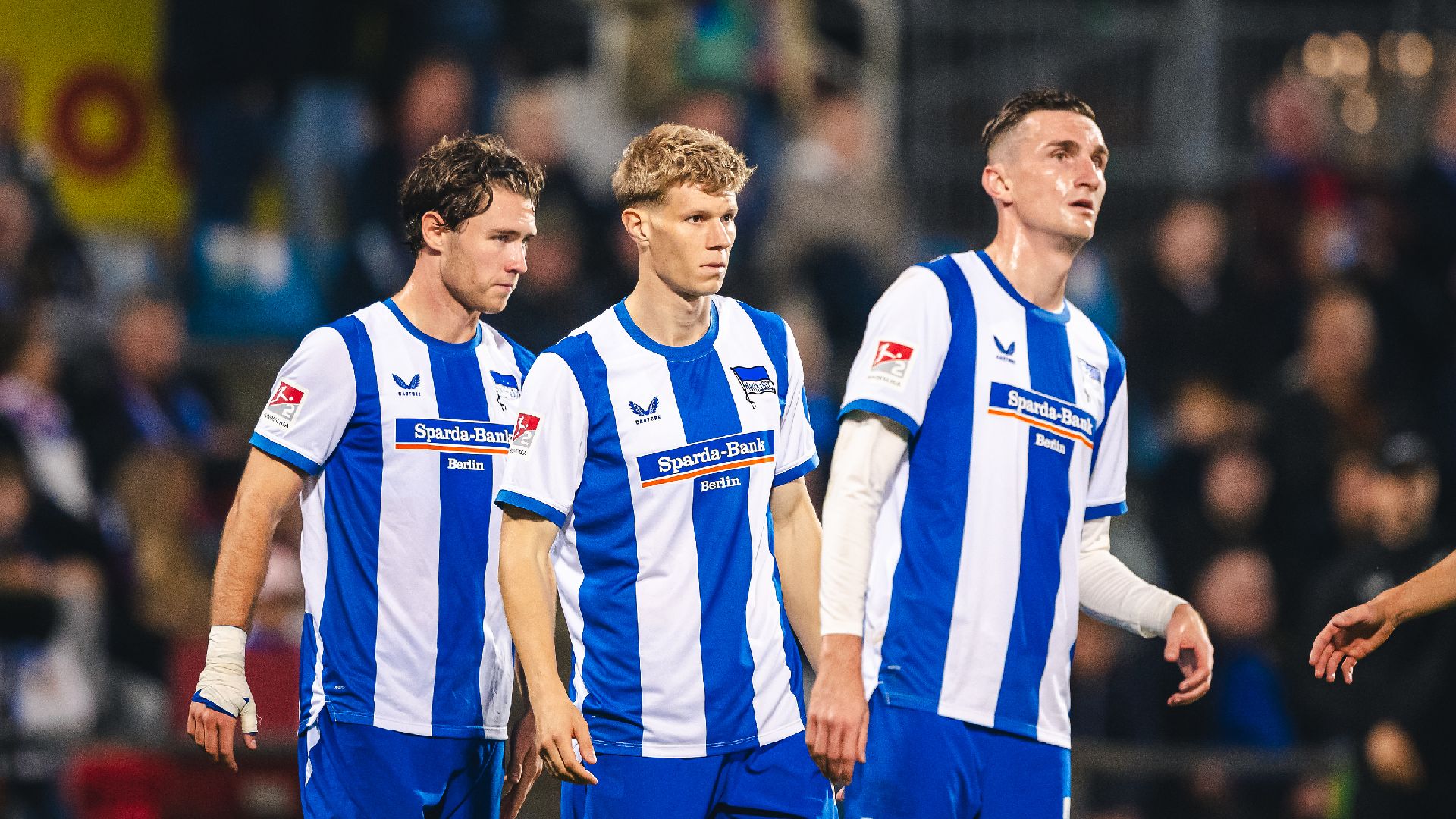 Linus Gechter, Luca Schuler und Niklas Kolbe stehen auf dem Rasen nebeneinander.